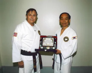 Congress_Smith_with_Jhoon_Rhee,_gettgin_black_belt-_looking_towards_camera.webp